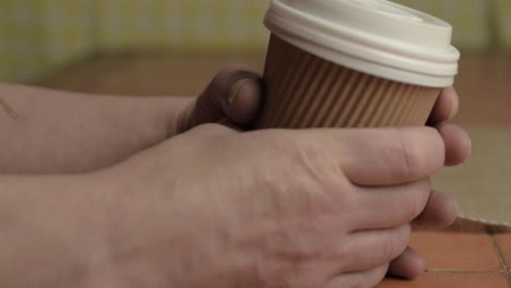 Hands-holding-a-takeaway-coffee-to-go-close-up