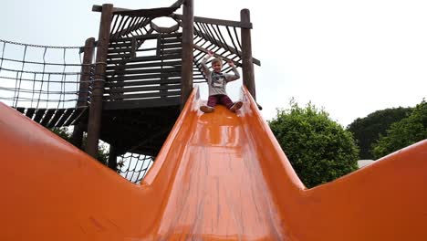 Caucasian-child-climbing-and-sliding-down-colourful-play-area-plastic-slide
