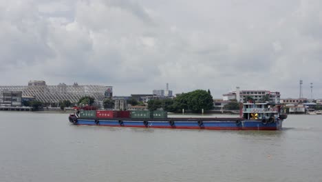 Chinese-river-barge-vessel-carrying-containers-underway-on-Zhujiang-River,-on-a-cloudy-day