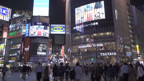 POV-walking-across-Shibuya-Scramble-in-Tokyo,-Japan-at-night-with-many-people