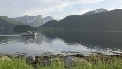A-boat-passing-by-in-idyllic-surroundings-at-a-lake-in-Norway