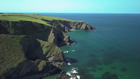The-beautiful-green-mountain-shoreline-of-Port-Isaac-Village-in-England--aerial