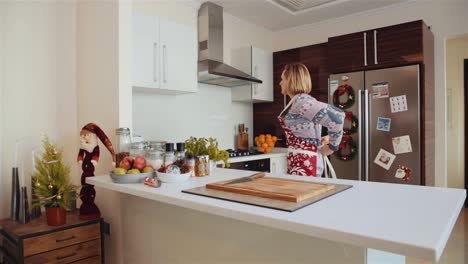 Woman-Puts-On-The-Apron-And-Gets-Ready-For-Cooking-In-The-Kitchen---Christmas-Time-In-The-House---medium-shot