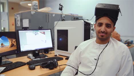 Arabischer-Mann-Mit-VR-Headset-Im-Büro-Schaut-Und-Lächelt-In-Die-Kamera-–-Mittlere-Aufnahme