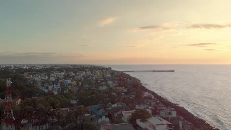 Aerial-Reveal-shot-of-Lighthouse-surrounded-by-buildings-through-the-golden-hour-shot-with-a-drone-in-4k