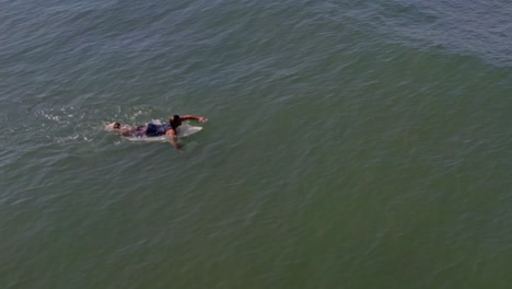 Aerial:-experienced-surfer-paddles-out-and-catches-large-wave-in-ocean