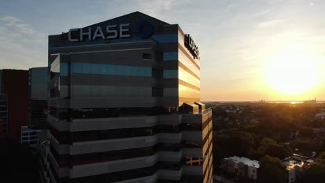 Sunrise-illuminates-JP-Morgan-Chase-Bank-skyscraper-in-downtown-city-center,-rising-aerial-shot