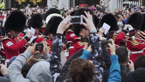 London-Queen's-Guard-cavalry-soldiers-play-musical-instruments-and-march-in-procession-with-spectators-watching-and-taking-photos,-handheld-close-up-slow-motion