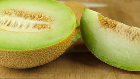 Tracking-shot-of-a-juicy-Galia-melon,-on-a-bamboo-cutting-board