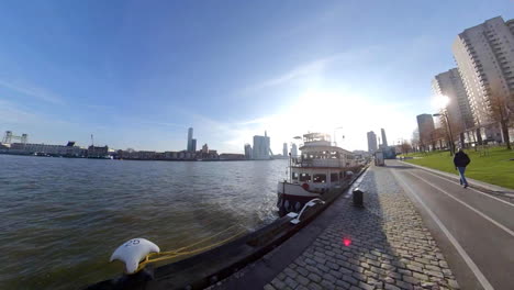 Pullback-Shot-Of-New-Meuse-River-In-Rotterdam,-Netherlands-With-Distant-View-Of-Erasmus-Bridge-From-Promenade---hyperlapse