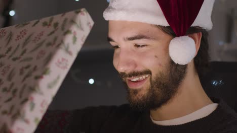 Mann-Schockiert-Und-überrascht-Beim-Öffnen-Des-Weihnachtsgeschenks,-Das-Sein-Gesicht-Aufleuchtet