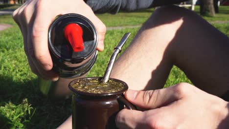 Close-up-shot-of-man-pouring-hot-water-into-a-"Mate",-making-and-classical-argentinian-infusion