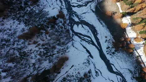 a-birds-eye-view-over-a-small-river-and-frozen-ground
