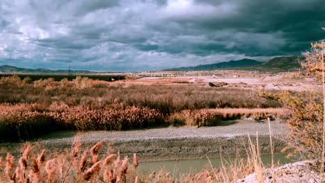 Stormy-windy-day-with-a-dramatic-cloudscape-over-the-river-and-mountains---static-time-lapse