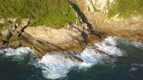 Aerial-closeup-shot-of-the-rugged-coastline-of-Trilha-da-Sepultura-at-golden-hour