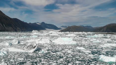 Icebergs-in-Glacial-Water-by-Alaskan-Coastline,-Aerial-View