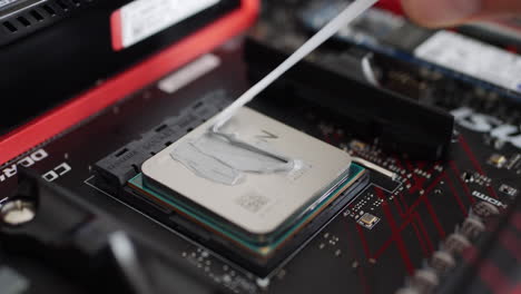 Ein-Computerreparaturtechniker-Installiert-Eine-AMD-Ryzen-2400G-CPU-Auf-Einem-Motherboard-Mit-Wärmeleitpaste-Zur-Luftkühlung