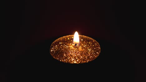 Auf-Einem-Dunkelroten-Hintergrund-Brennt-Eine-Goldene-Kerze-Mit-Wunderschönem-Funkeln