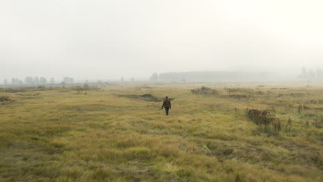 Junger-Dokumentarfilmer-Watet-Durch-Hohes-Gras,-Nebliges-Moorland,-Tschechien