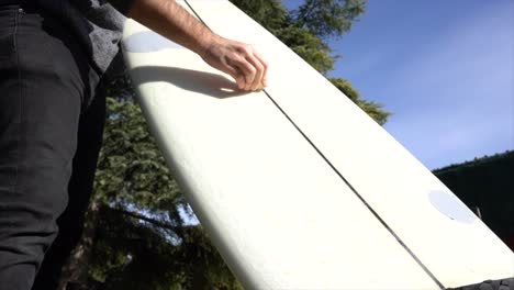Low-angle-view-of-a-surfer-waxing-the-board-in-the-garden