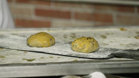 Placing-Raisin-Cookie-Dough-On-A-Baking-Peel-In-The-Bakery-Kitchen---close-up,-slow-motion