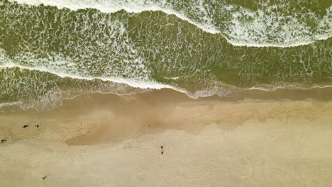 White-Foamy-Waves-On-Seashore-With-Tourist-Walking-During-Daytime-In-Wladyslawowo,-Poland