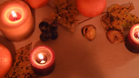 Close-up-of-an-autumnal-background-with-leaves,-mandarin,-chestnuts,-grapes-and-candles
