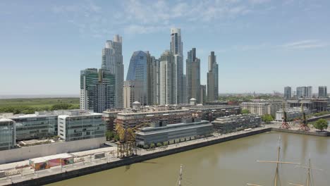 Aerial-View-Of-Puerto-Madero-Promenade-In-Buenos-Aires,-Argentina-On-A-Sunny-Day-With-City-Skyline-In-Background---drone-shot