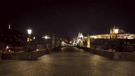 A-magnificent-view-of-the-paved-causeway-of-Charles-bridge-in-the-historical-centre-of-Prague,-Czechia,-at-night,-with-no-people,-statues-and-lanterns-on-both-sides,-Prague-castle-in-the-background