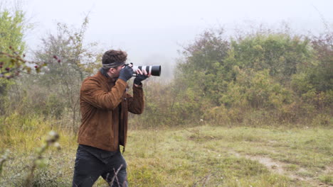 Wildlife-photographer-with-a-DSLR-camera-taking-photos-in-bushes,mist
