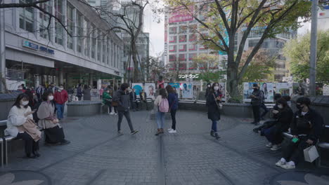Hachiko-Gedenkstatue-In-Der-Stadt-Shibuya,-Tokio,-Japan-–-Menschen-Mit-Gesichtsmaske-Gehen-Und-Sitzen-Während-Einer-Pandemie-Auf-Einer-Bank-In-Der-Nähe-Der-Hachiko-Statue