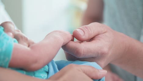 Close-up-of-father-touching-his-new-born-baby's-hand