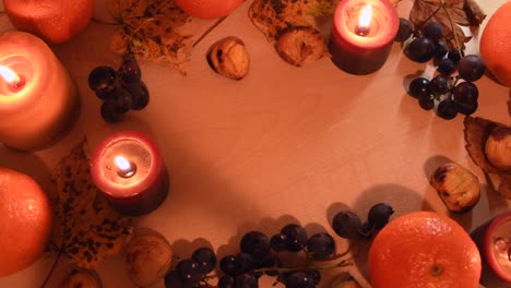Top-view-of-an-autumnal-background-with-leaves,-mandarin,-chestnuts,-candels-and-grapes