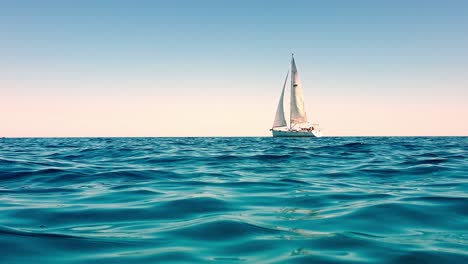 Low-angle-view-of-small-white-yacht-boat-sailing-slowly-in-calm-open-sea
