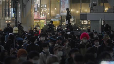 Fotografen-Fotografieren-Die-Menschenmenge,-Die-In-Der-Halloween-Nacht-Am-Shibuya-Kreuzung-Drängelt,-Während-Polizisten-Wache-Halten-–-Statische-Aufnahme,-Zeitlupe