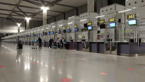 Airport-Counter-Check-in---Passengers-At-The-Counter-Check-in-Area-Of-Malaga-Airport-Observing-Social-Distancing---New-Normal-In-Malaga,-Spain---long-shot
