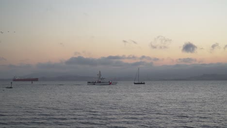 A-US-Coast-Guard-Boat-Passes-a-Sail-Boat-in-the-San-Francisco-Bay-During-the-Evening