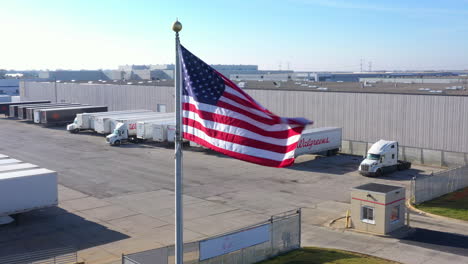 Bandera-De-Estados-Unidos-Ondeando-Orgullosamente-Sobre-El-Estacionamiento-Ilimitado-De-Camiones-De-La-Compañía-De-Transportistas-En-Chicago