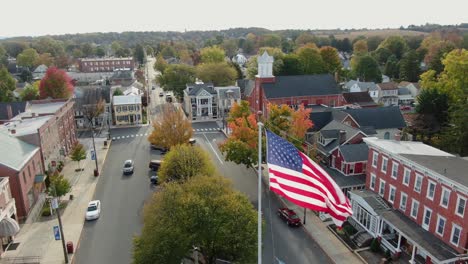 Close-up-aerial-of-US-American-flag-waving-above-Main-Street-in-Small-Town-America-square