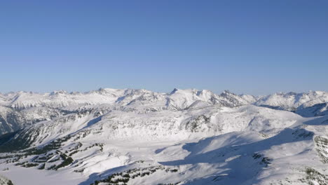 Sonnenlicht-Durch-Schneebedeckte-Bergrücken-Vor-Blauem,-Klarem-Himmel-In-Kanada