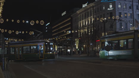 Three-trams-pass-on-a-street-decorated-with-Christmas-lights-at-night