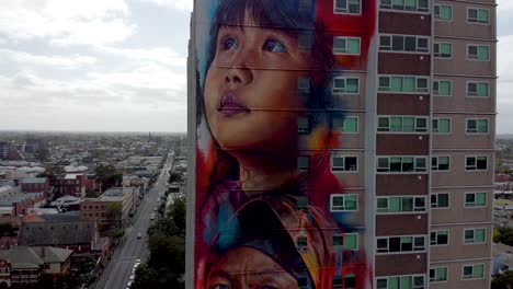 Drone-shot-of-a-beautiful-tower-mural-in-Melbourne,-Australia-that-represents-the-diversity-of-residents-and-migrants-living-in-the-country