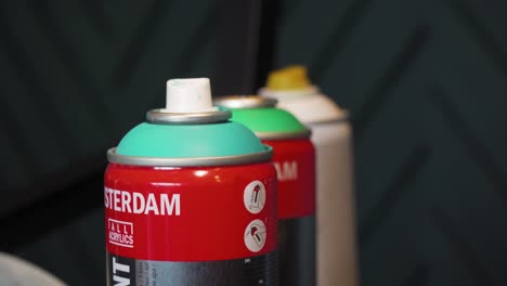 Spray-paint-bottles-close-up,-hand-reaching-for-aerosol-can,-graffiti-street-art