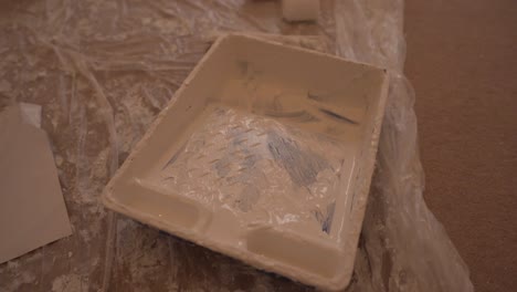 Close-view-of-white-painting-tray-for-paint-mixture-on-the-plastic-cover-floor