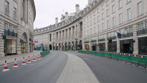 Lockdown-in-London,-gimbal-walk-along-empty-Regent-Street-during-2020's-Coronavirus-pandemic,-with-Coronavirus-barriers,-cones-and-signs-in-the-road