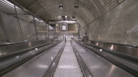 POV-Of-A-Person-Going-Up-By-An-Escalator-And-Looking-Down-Inside-Nationaltheatret-Station-In-Oslo,-Norway-During-Pandemic