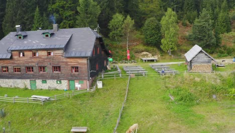 Aerial-shot-of-big-wooden-house-with-a-farm-near-forest-at-Sostanj