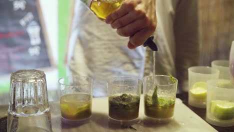 Barman-pouring-alcohol-into-cups-with-lime-in-a-bar