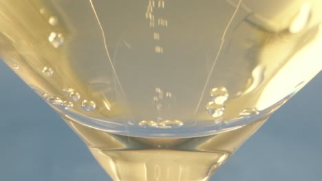 Macro-closeup-shot:-a-cocktail-glass-full-of-ouzo-,-with-bubbles-rising-up