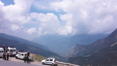 Low-angle-shot-of-sunny-weather-clouds-and-mountain-with-tourist-standing-with-the-car-in-the-street-of-Manali-India